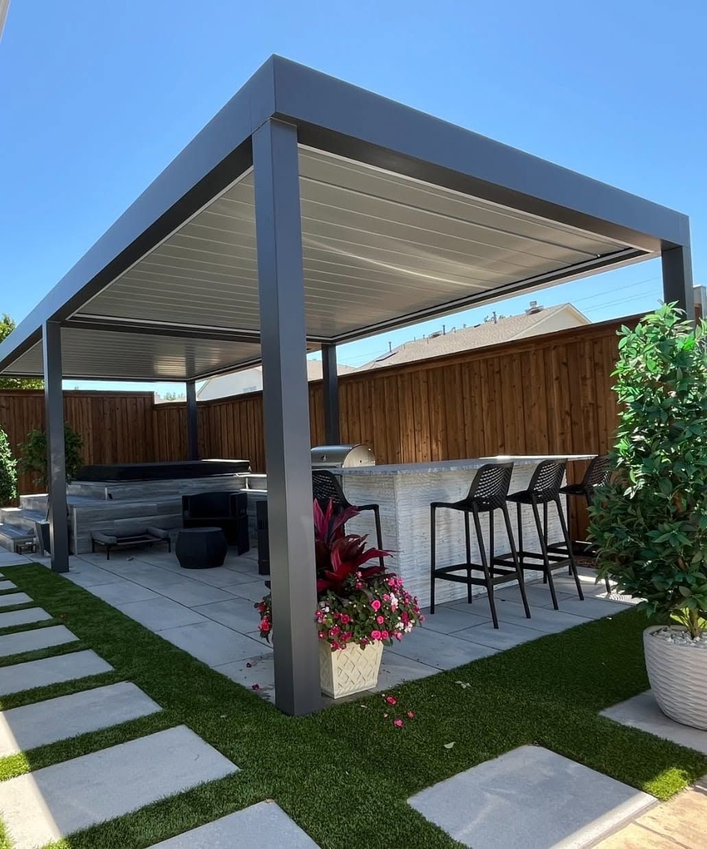 Modern louvered pergola over a bar and spa with turf and concrete pads
