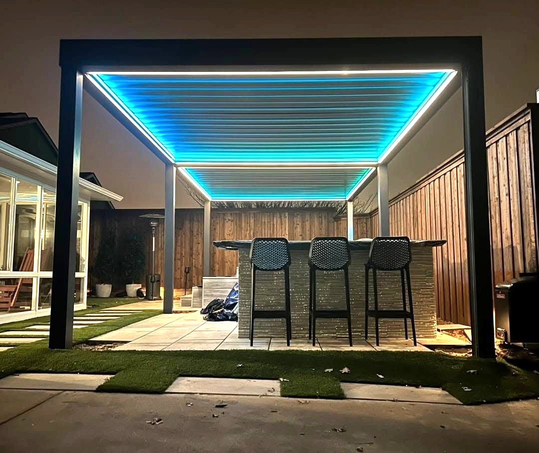 Louvered patio cover lit at night over a furnished outdoor seating area