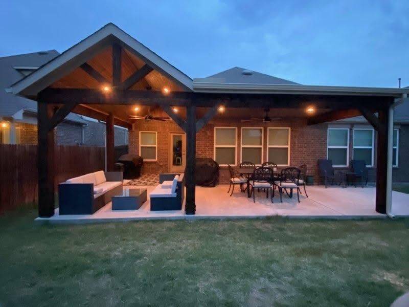 Gable patio cover lit at dusk over a furnished patio